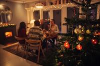 Family sitting at dinner table in background of a Christmas tree